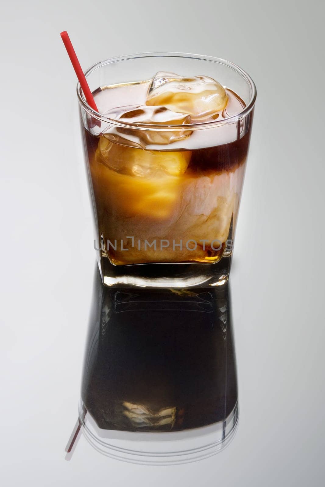 White Russian mixed drink on a grey background with reflection
