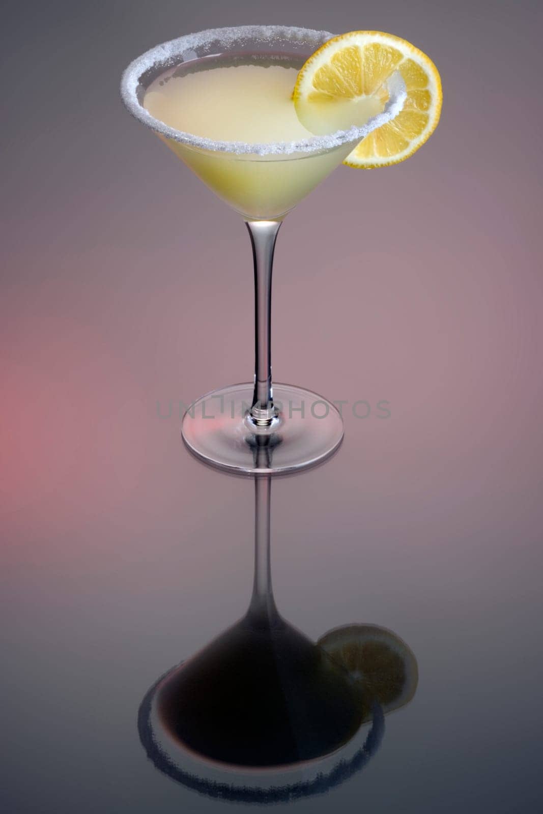 Lemon Drop mixed drink with lemonslice garnish on a red and grey background with reflection