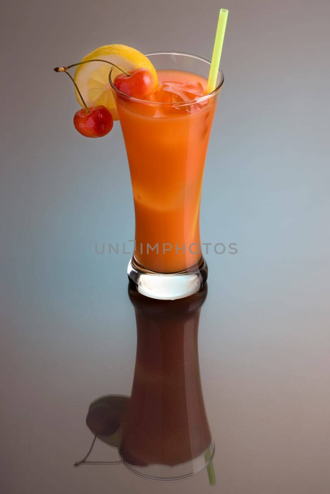 Zombie mixed drink with cherry and lemon garnish on grey background with reflection