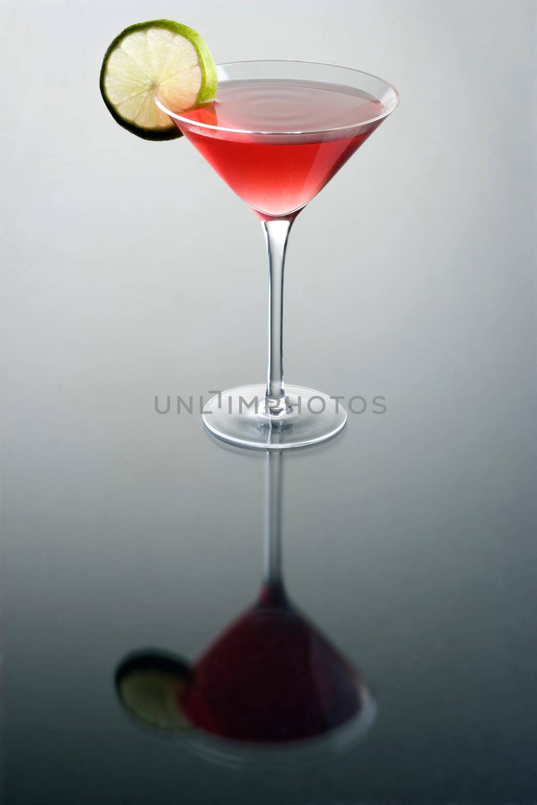 Cosmopolitan cocktail with lime slice on grey background