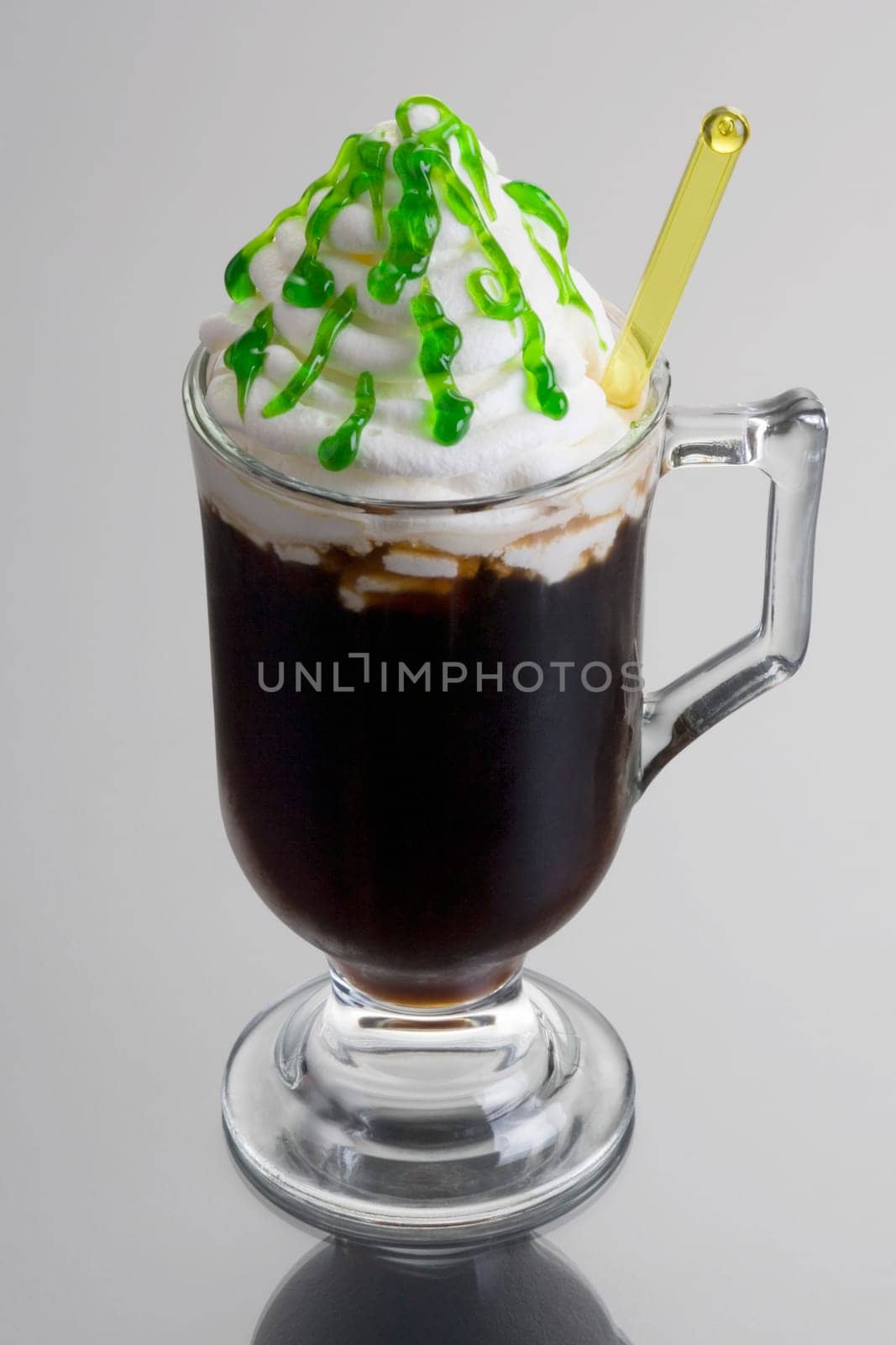 Irish Coffee mixed drink dressed up for St. Patrick's Day on grey background with reflection