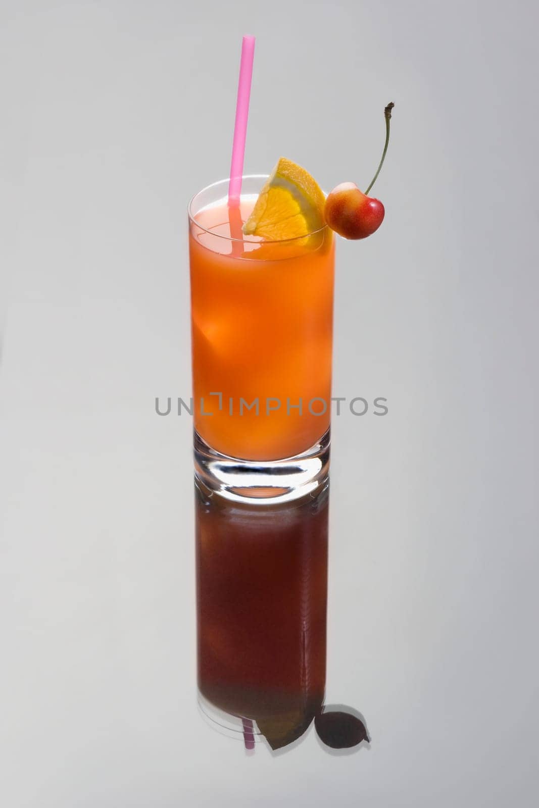 Seabreeze mixed drink with lime and cherry garnish on a grey background