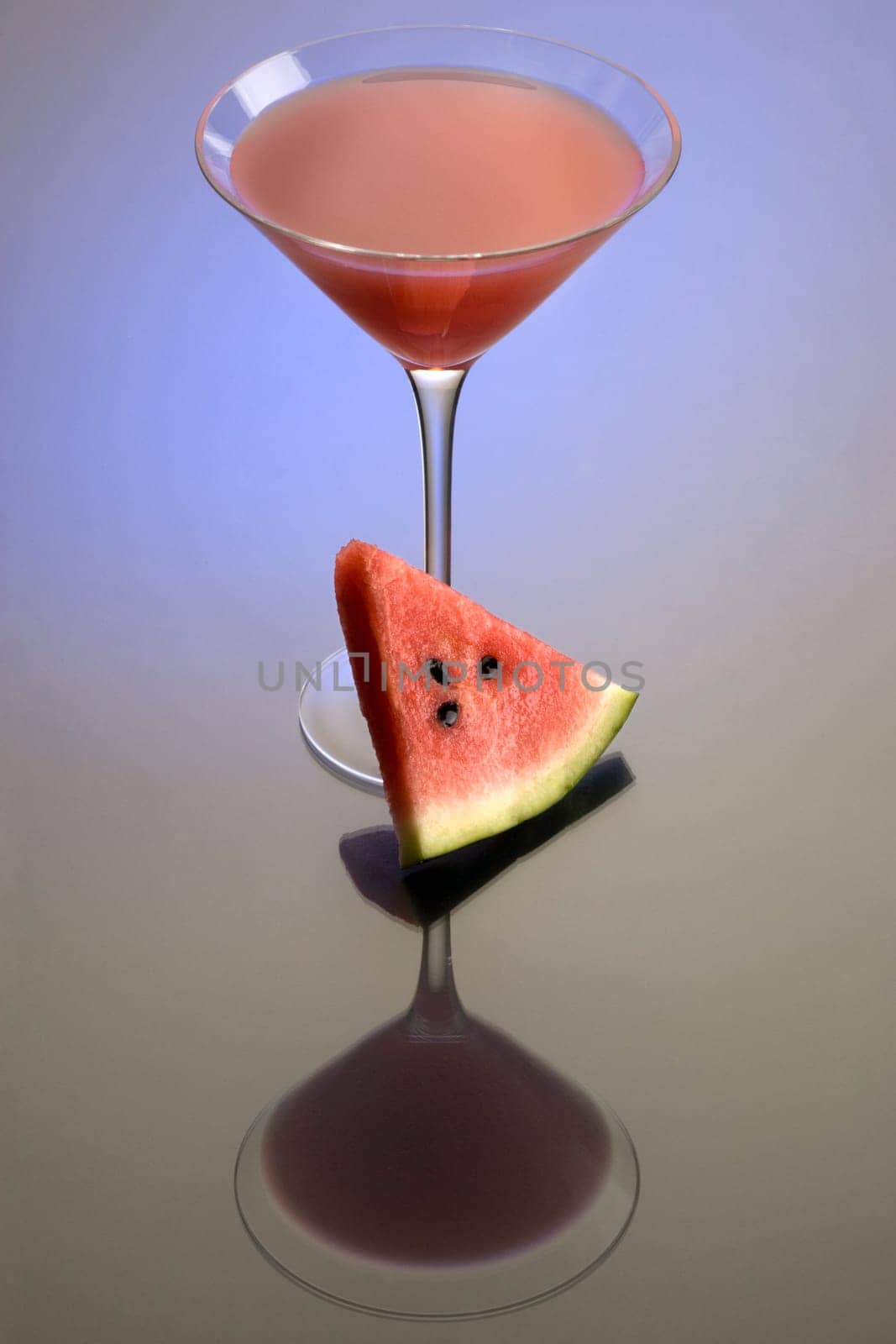 Watermelon Martini mixed drink with melon garnish on grey background with reflection