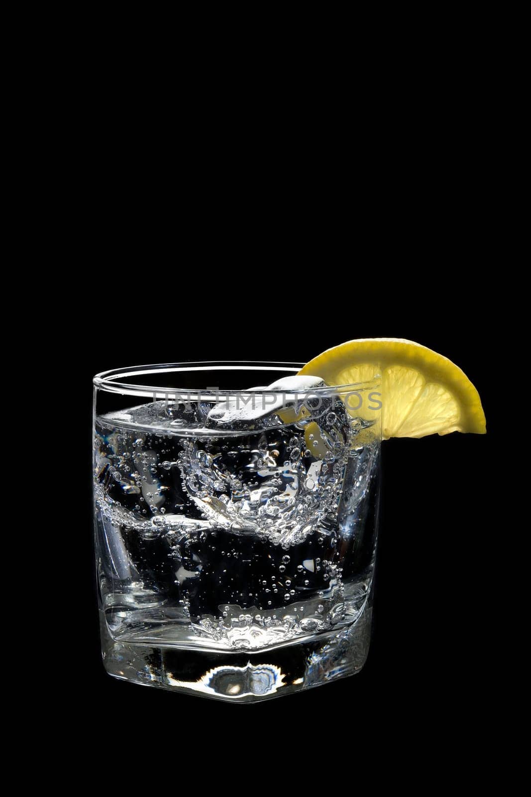 Club soda or Vodka / Gin and tonic mixed drink with lemon slice on a black background