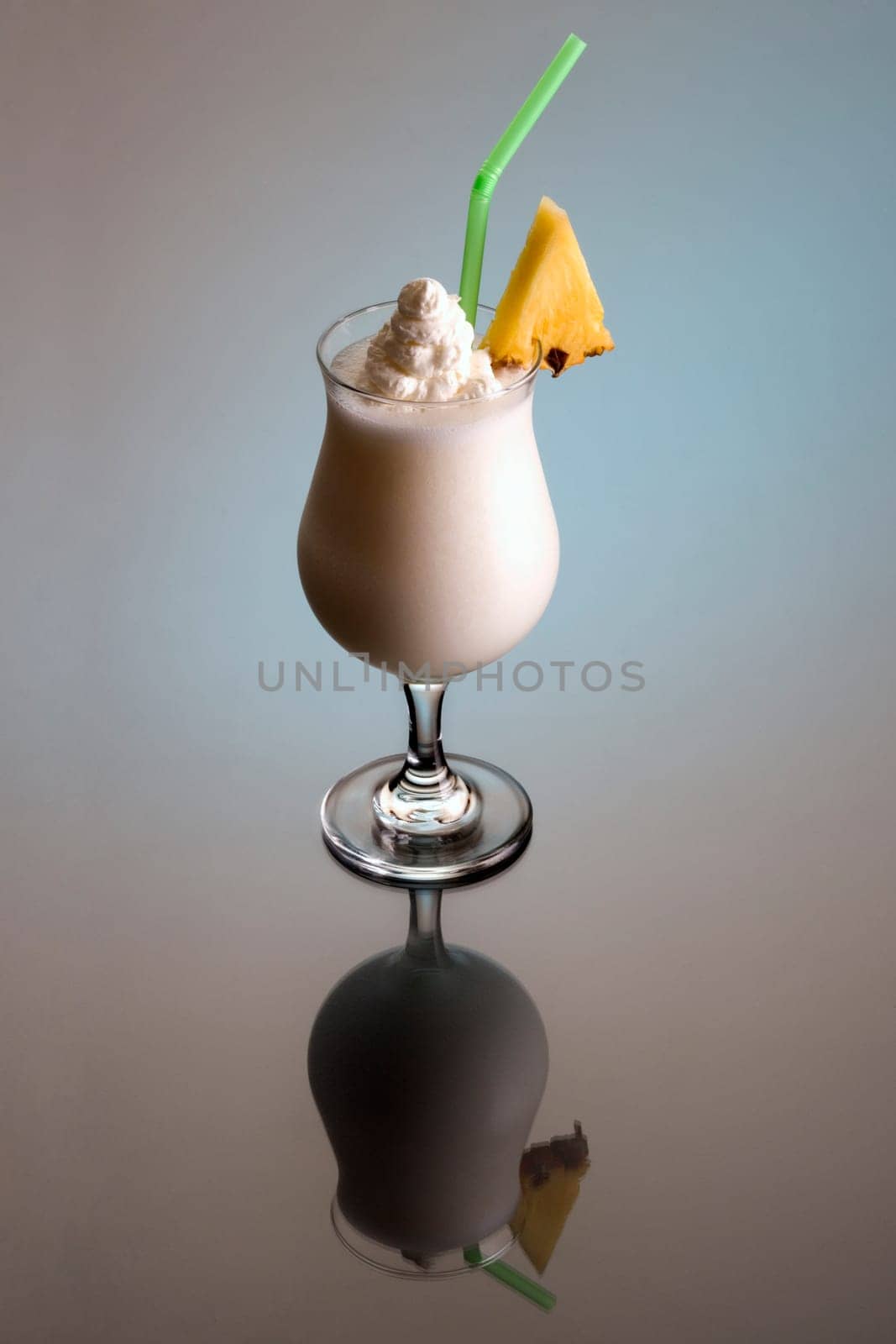 Pina Colada mixed drink with pineapple garnish on plain background with reflection