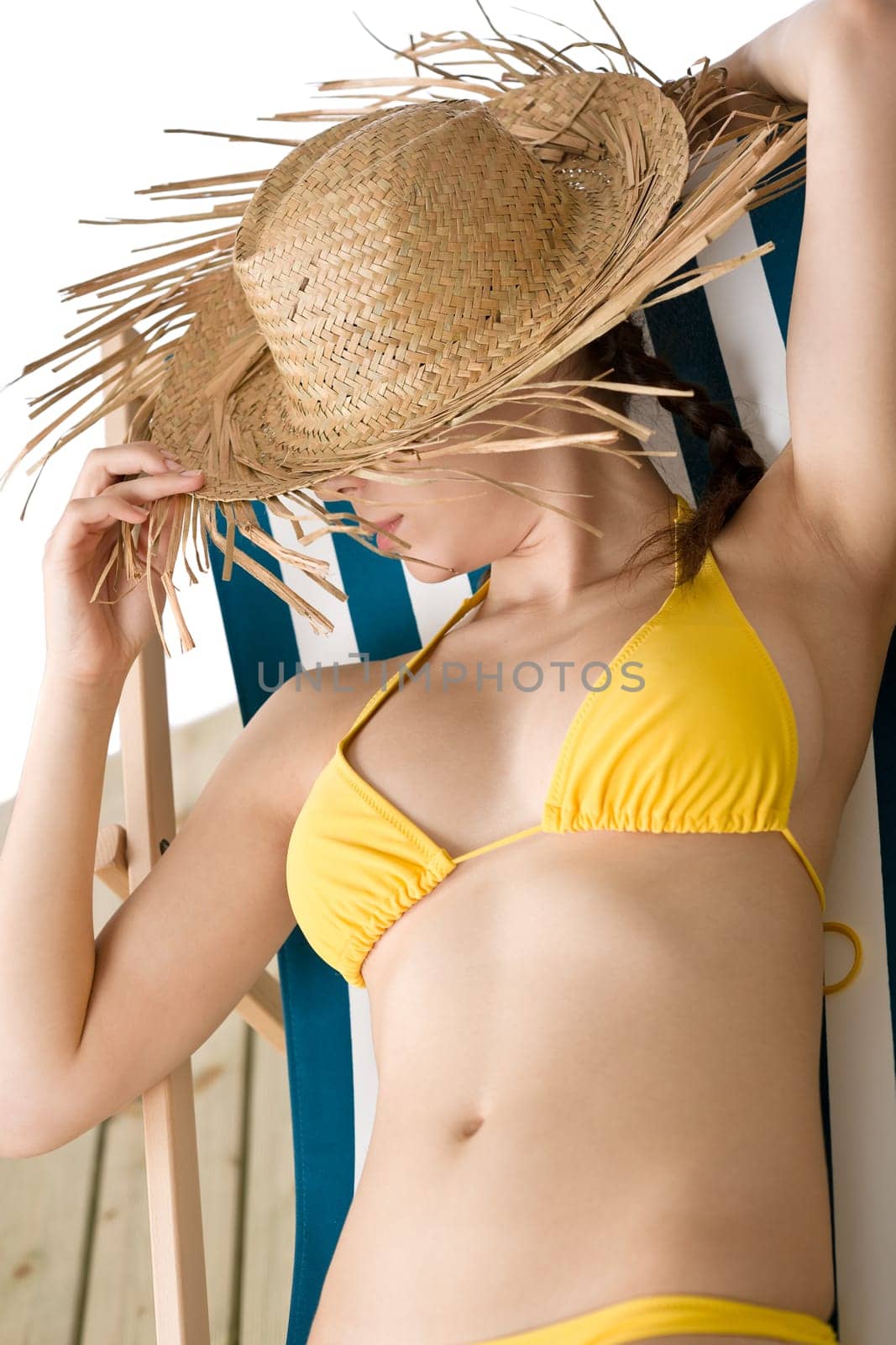 Beach - woman with straw hat in yellow bikini sunbath