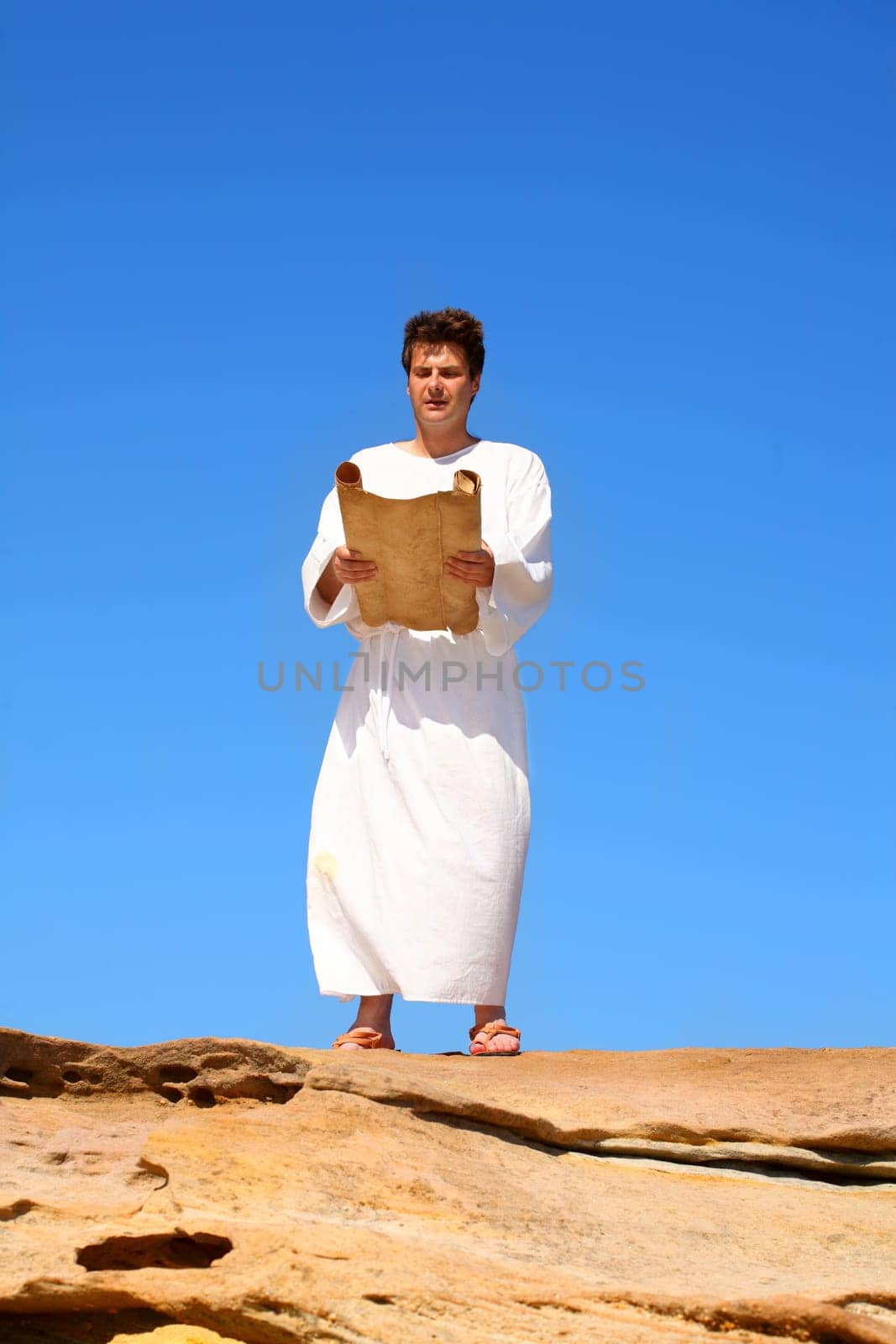 man reading scroll in rocky desert land scape