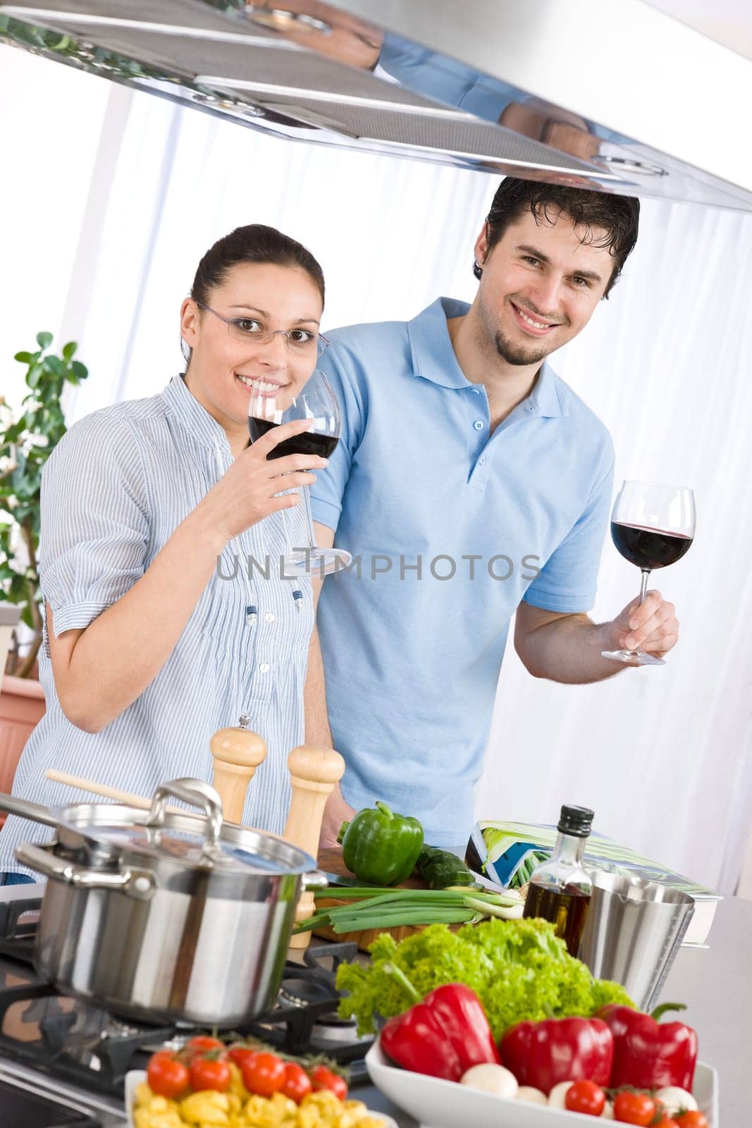 Smiling couple drink red wine cooking in kitchen