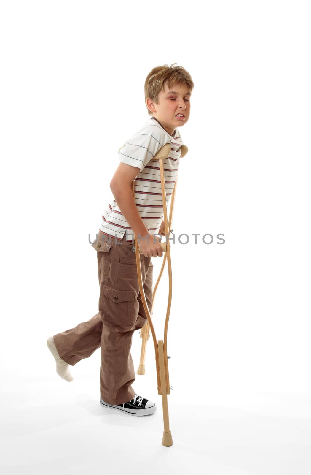 Wincing injured boy using crutches