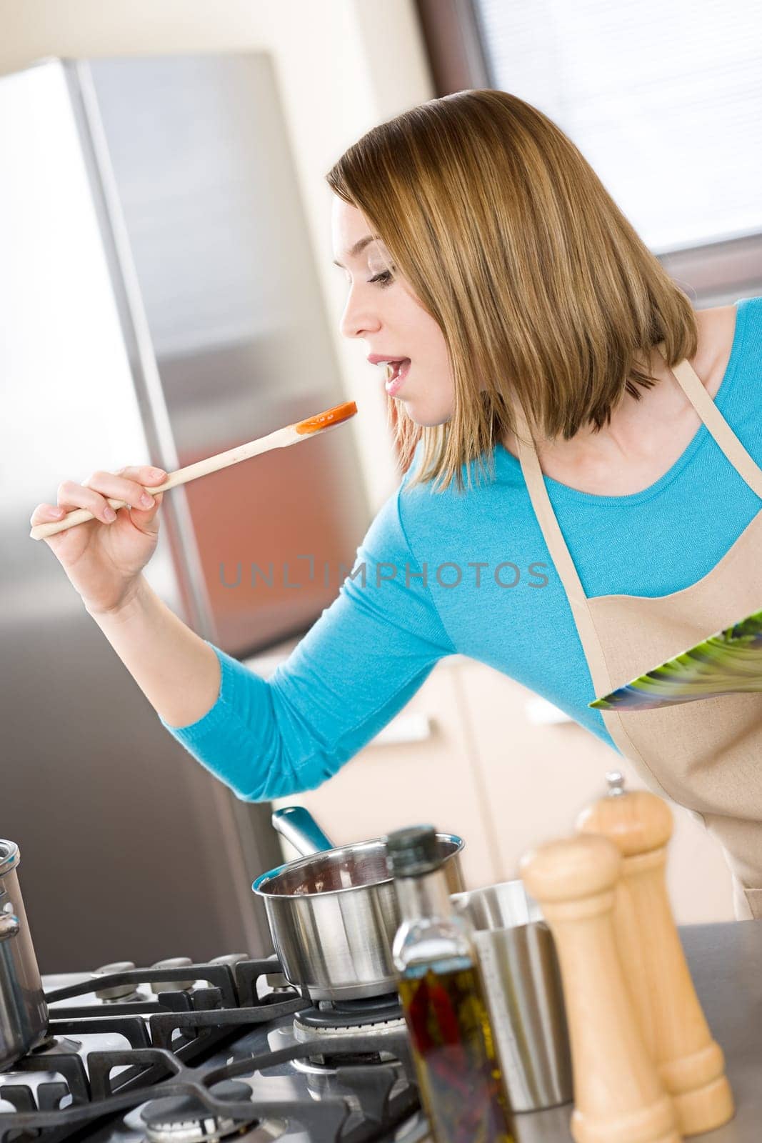 Cooking - Woman tasting Italian tomato sauce in modern kitchen