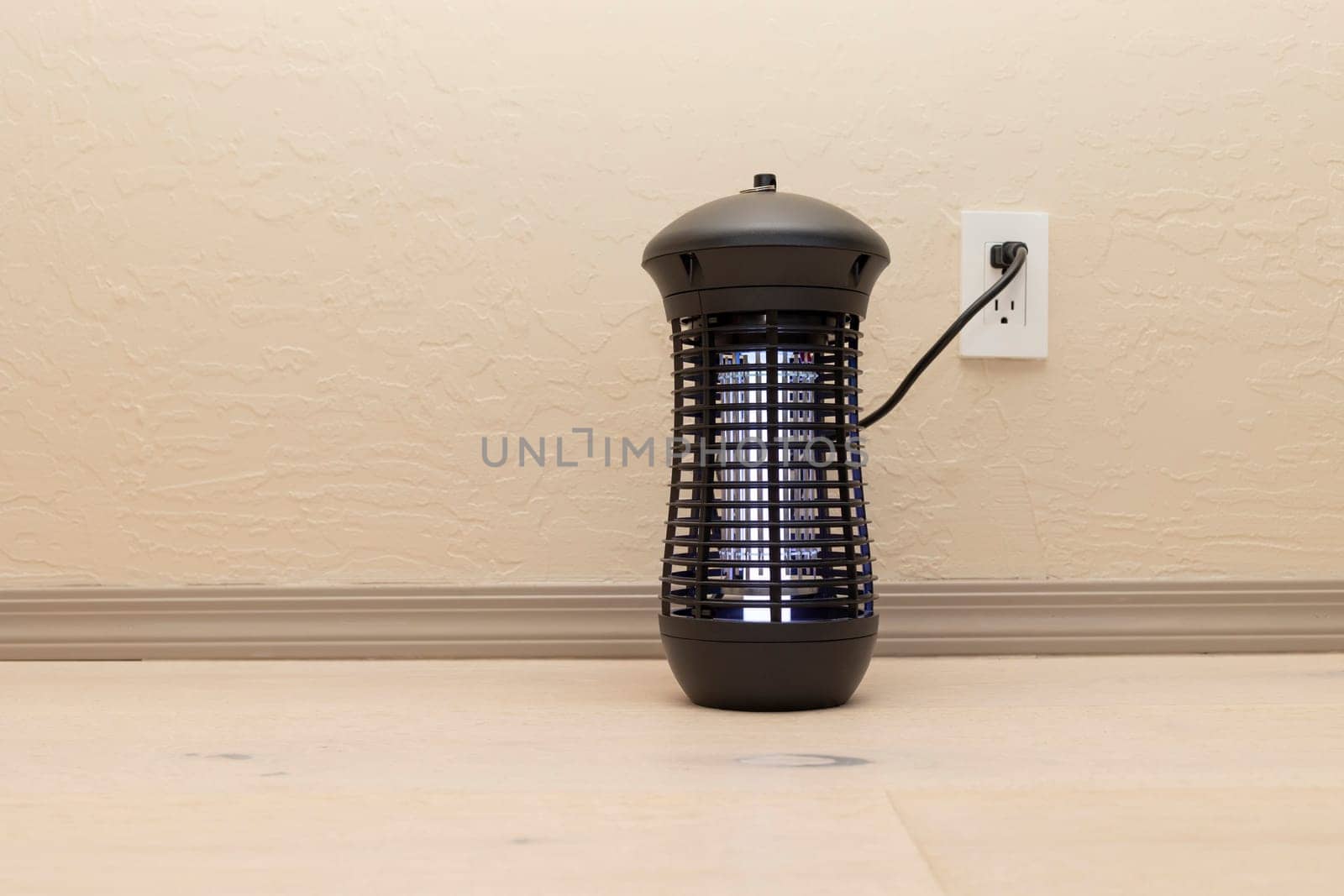 Electric Hanging Bug Killer Lamp . Mosquito and Insect Zapper With Blue Purple Lights .on Wooden Floor in Room. Fly Trap for Outdoor and Indoor. Copy Space For Text. Horizontal Plane.