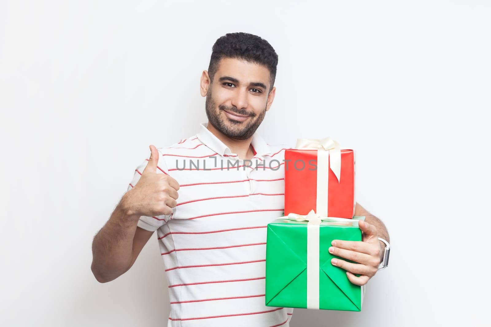 Cheerful joyful young bearded man looking at camera, holding two gift boxes, showing like gesture. by Khosro1