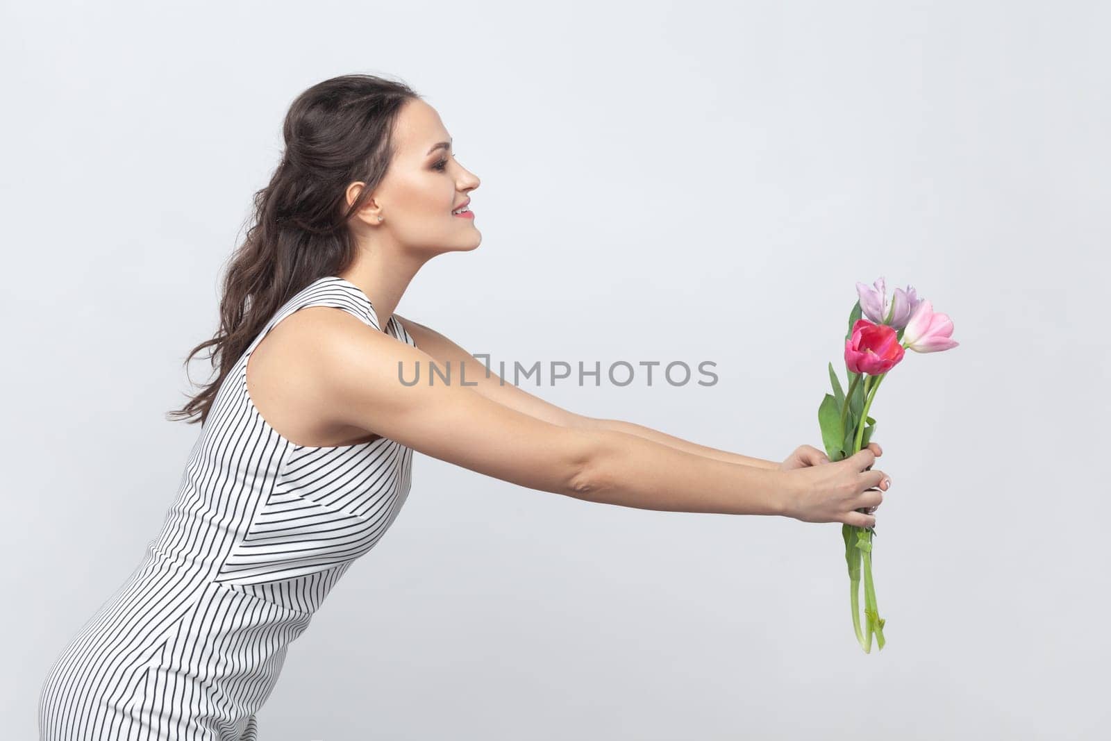 Pretty positive woman holding bouquet of tulips, giving it to her mother, congratulating on 8 March. by Khosro1