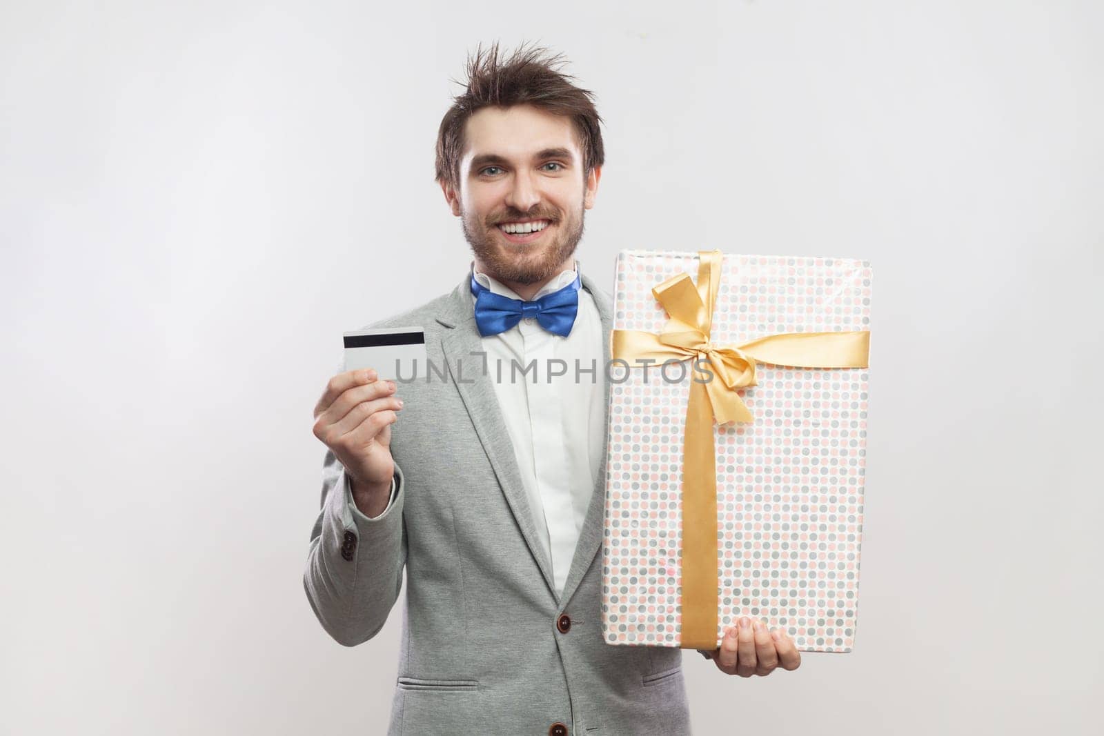 Joyful cheerful smiling bearded man standing with present box and showing credit card. by Khosro1