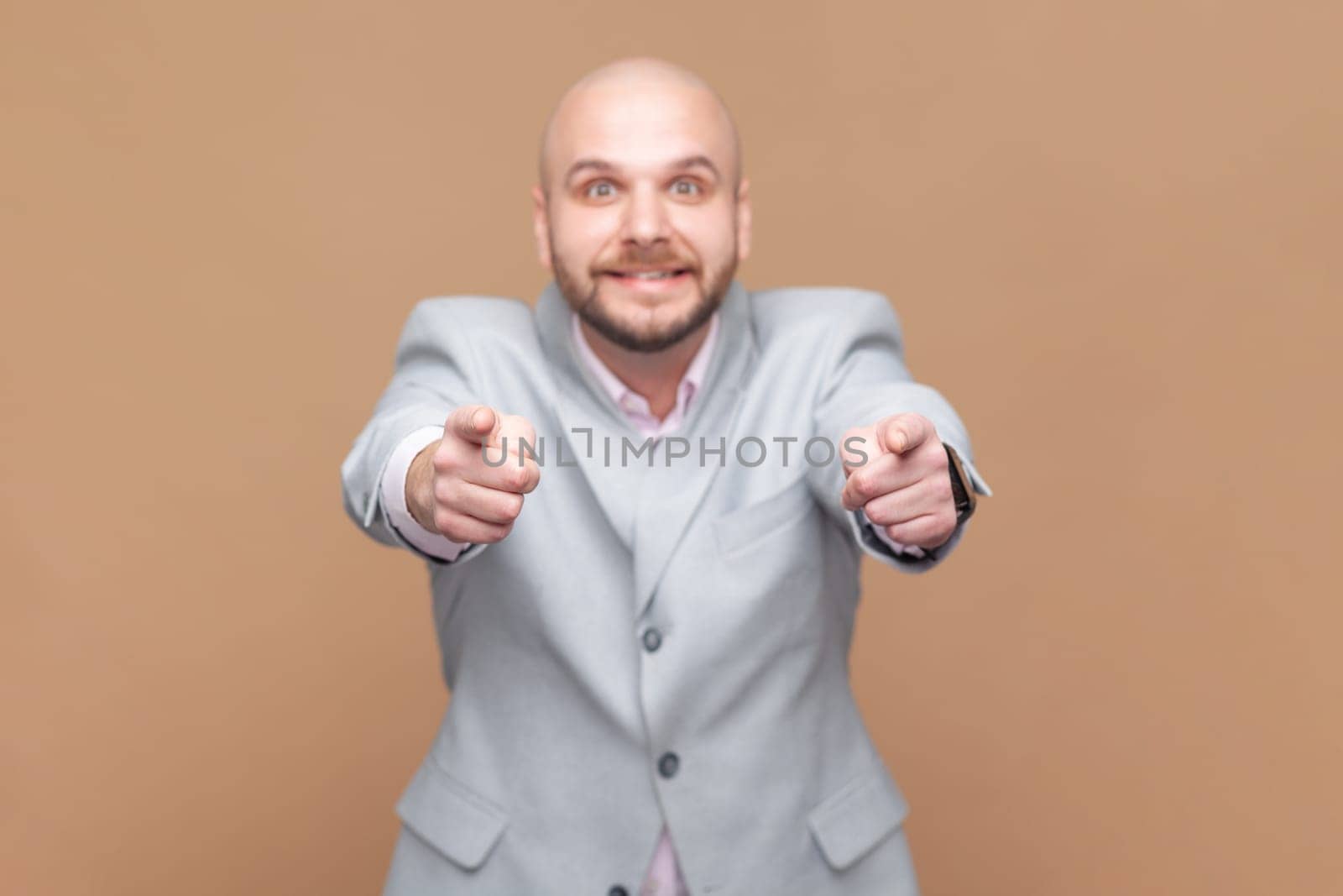 Man pointing to you, has joyful expression, looking at camera with toothy smile, wearing gray jacket by Khosro1
