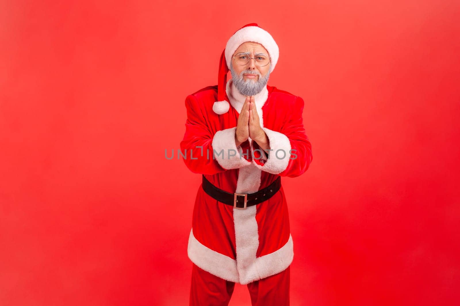 Forgive me or give me one chance more. Elderly man with gray beard wearing santa claus costume standing with palm hands, looking and begging. by Khosro1