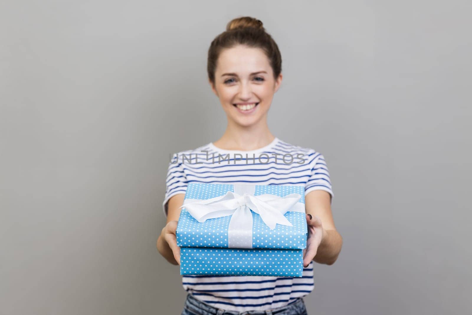 Woman holding out present box, giving gift, looking at camera with optimistic expression, greeting. by Khosro1