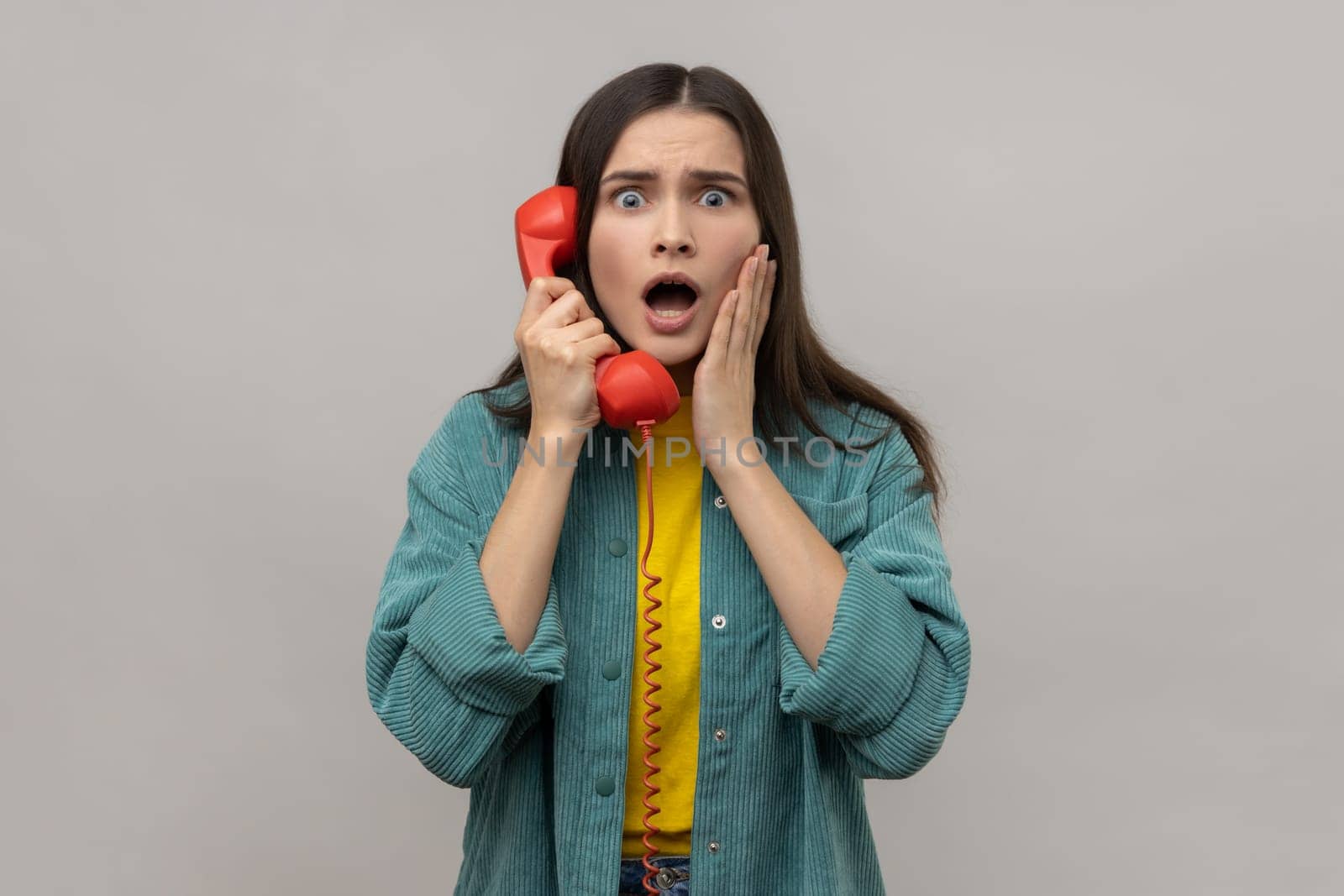 Amazed woman holding phone handset surprised by conversation open mouth shocked by unbelievable news by Khosro1