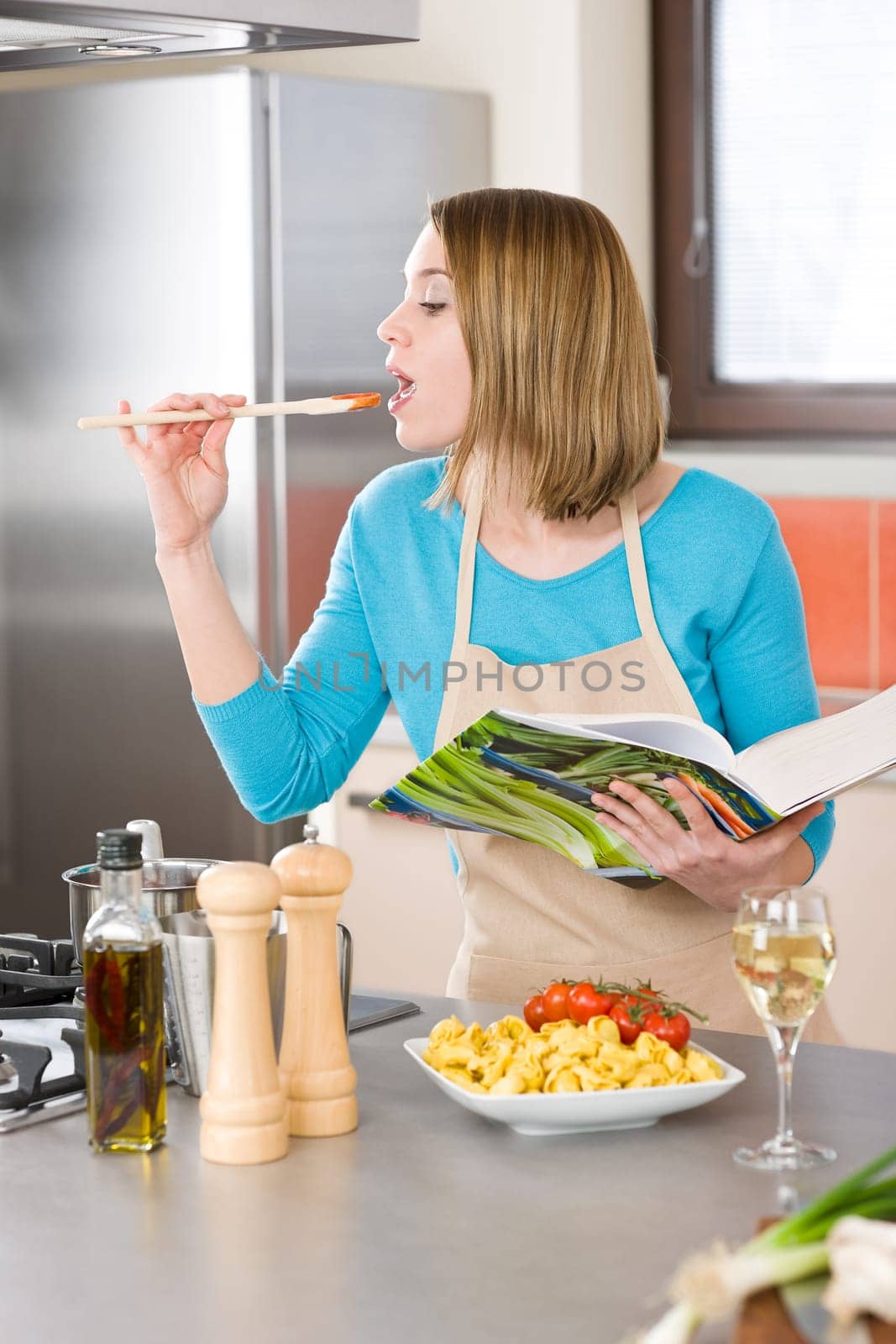 Cooking - Woman tasting Italian tomato sauce in modern kitchen