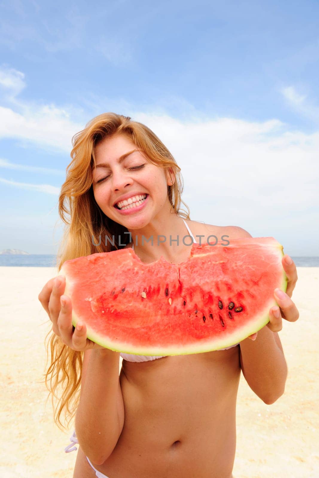 Woman eating watermelon on the beach