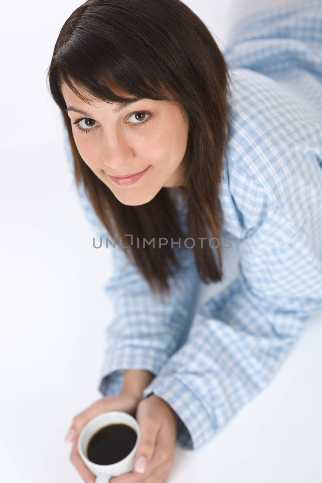 Happy young woman with coffee in pajamas