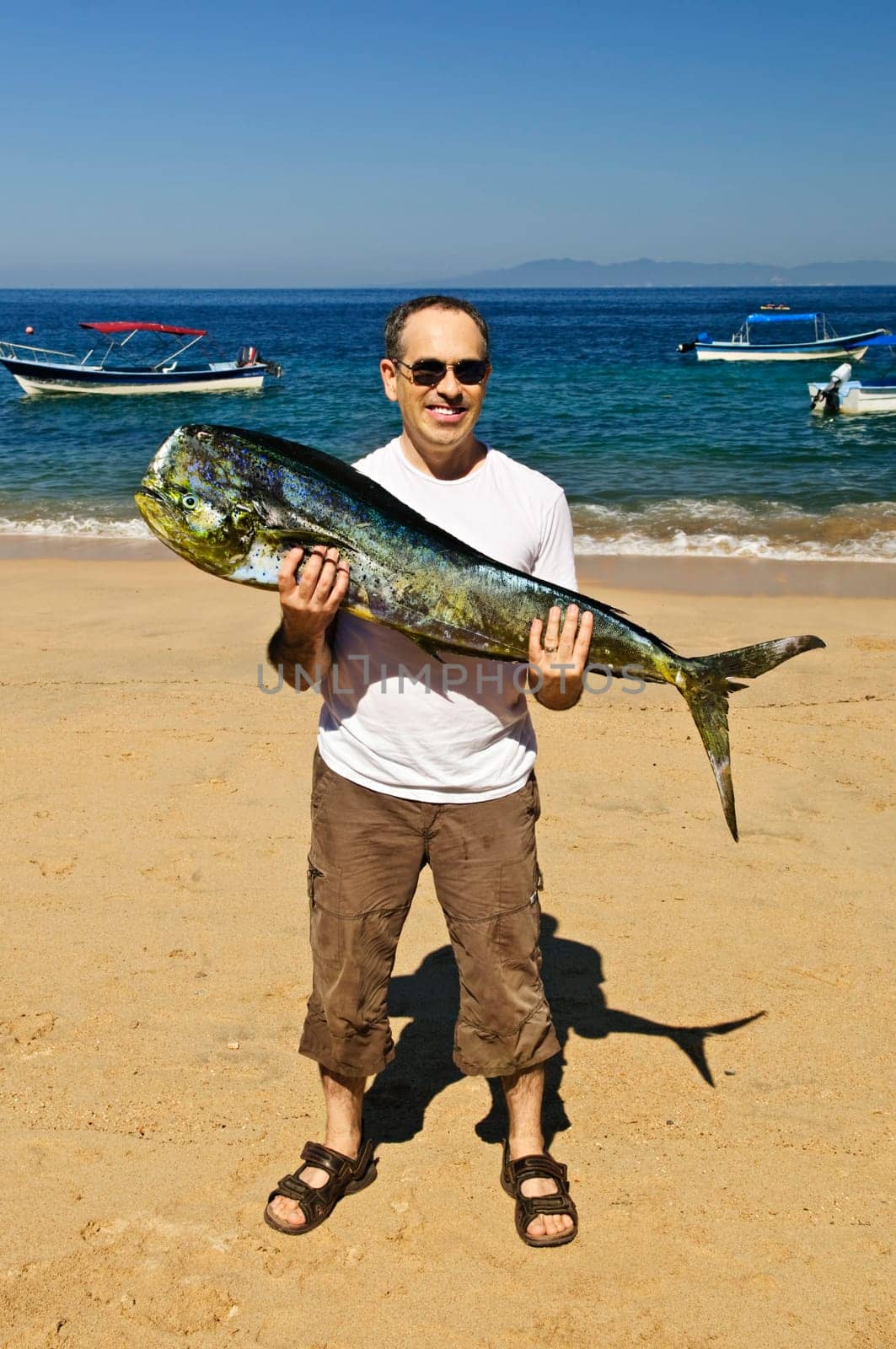 Tourist holding big fish on beach