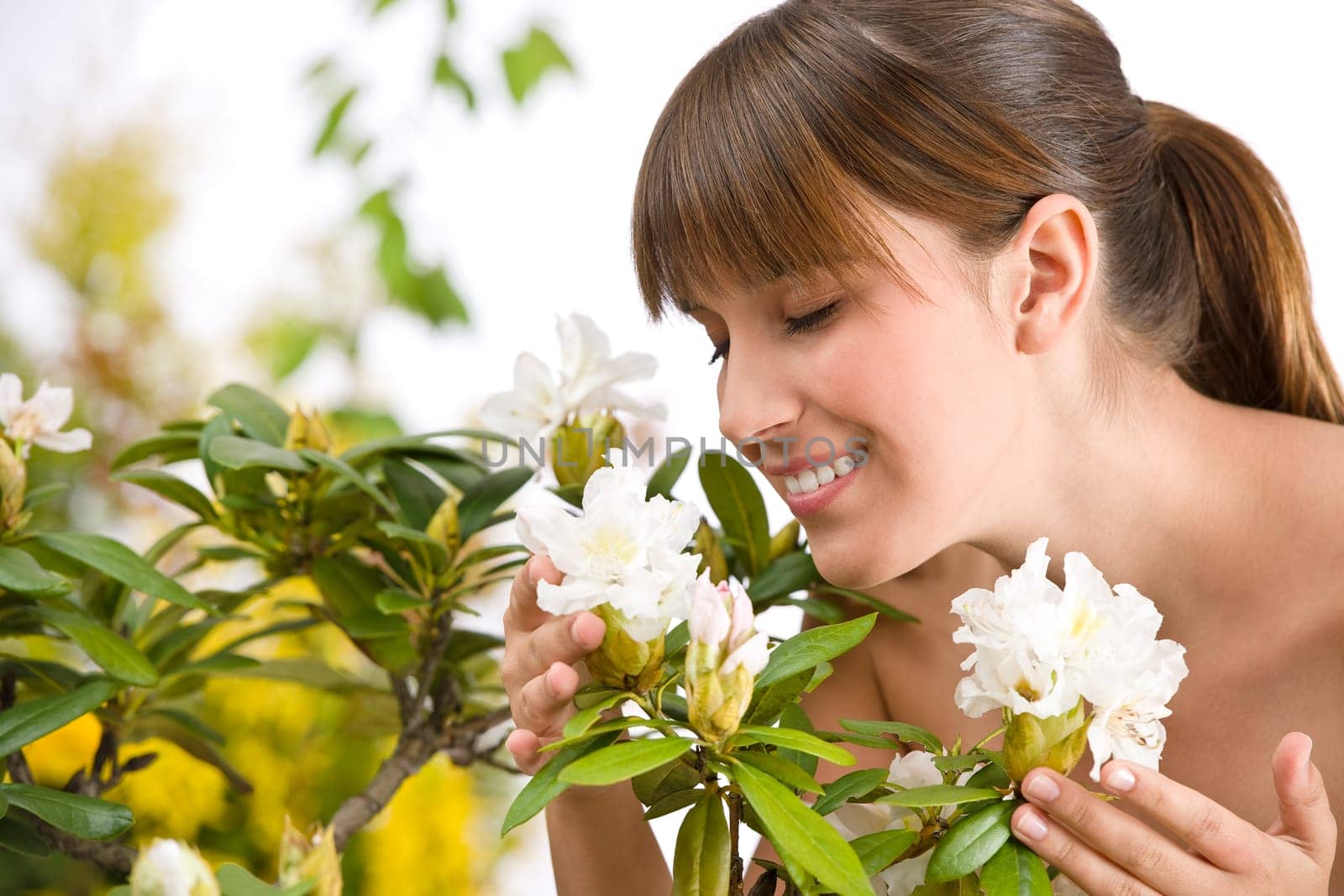Portrait of woman smelling blossom of Rhododendron flower