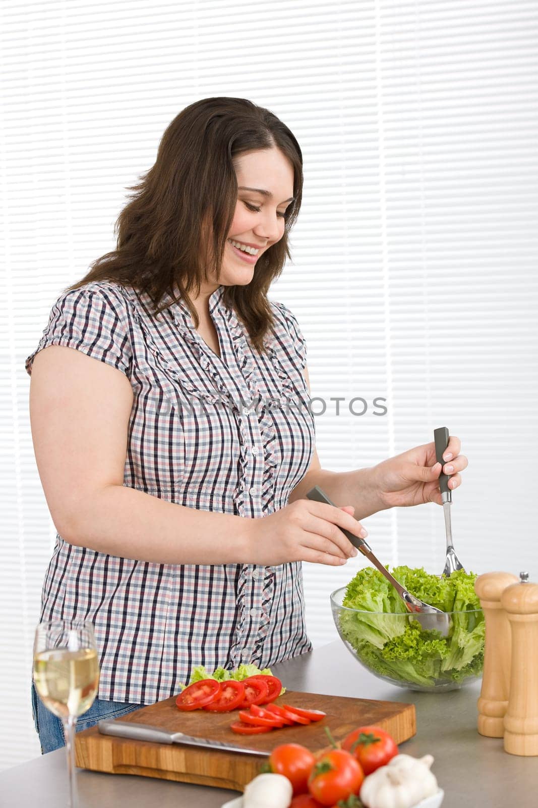 Cook - Plus size happy woman preparing salad in kitchen