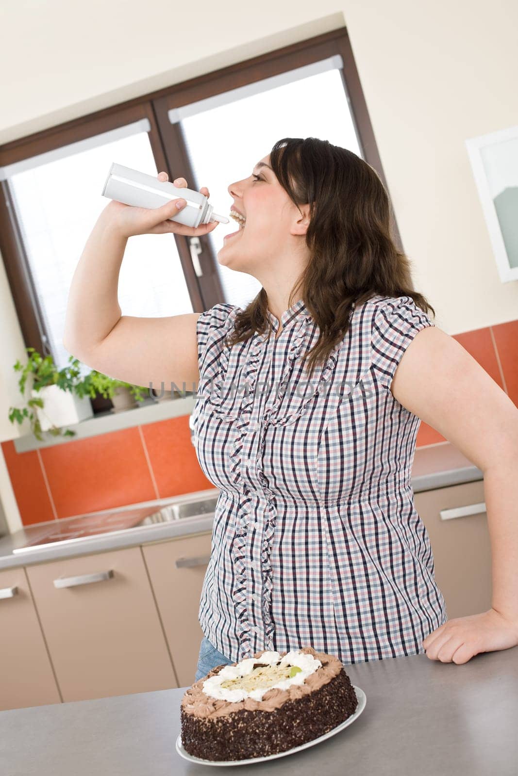 Plus size woman eat whiped cream in modern kitchen