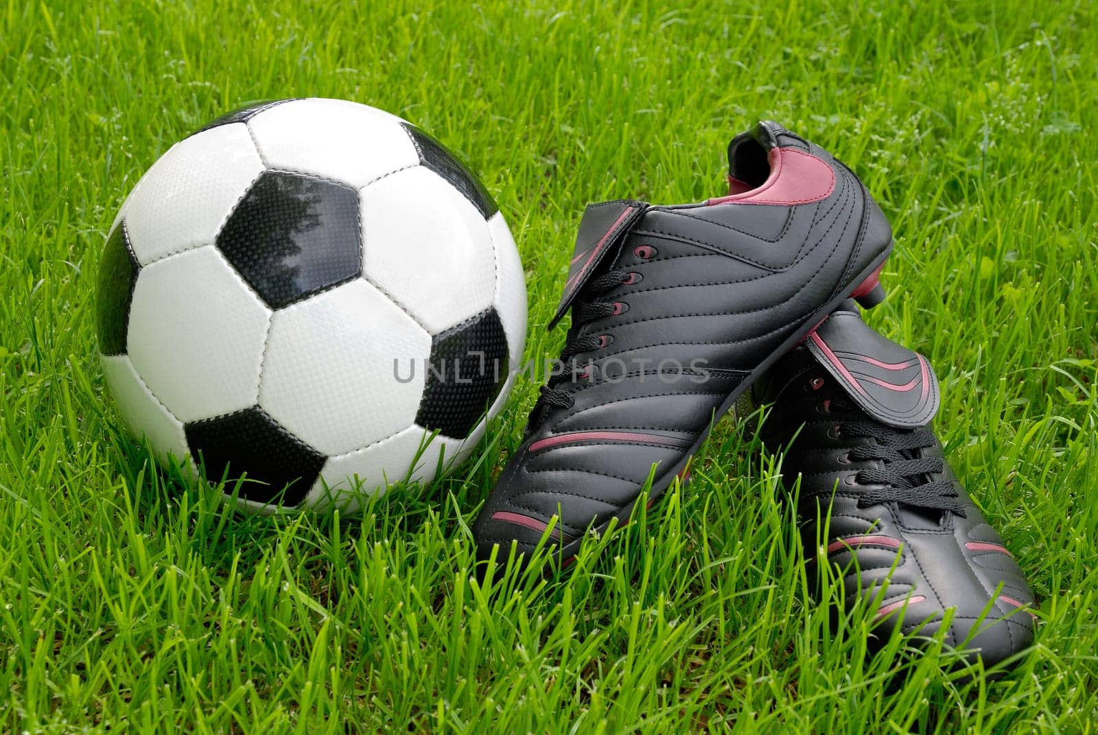 Football boots and ball on grass