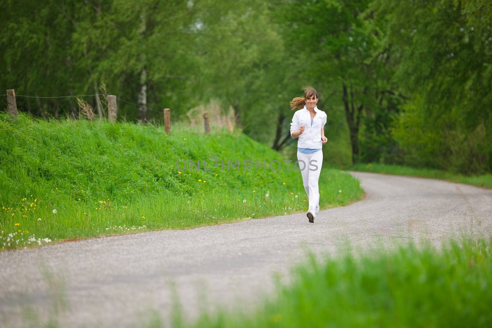Jogging - sportive woman running on road in nature