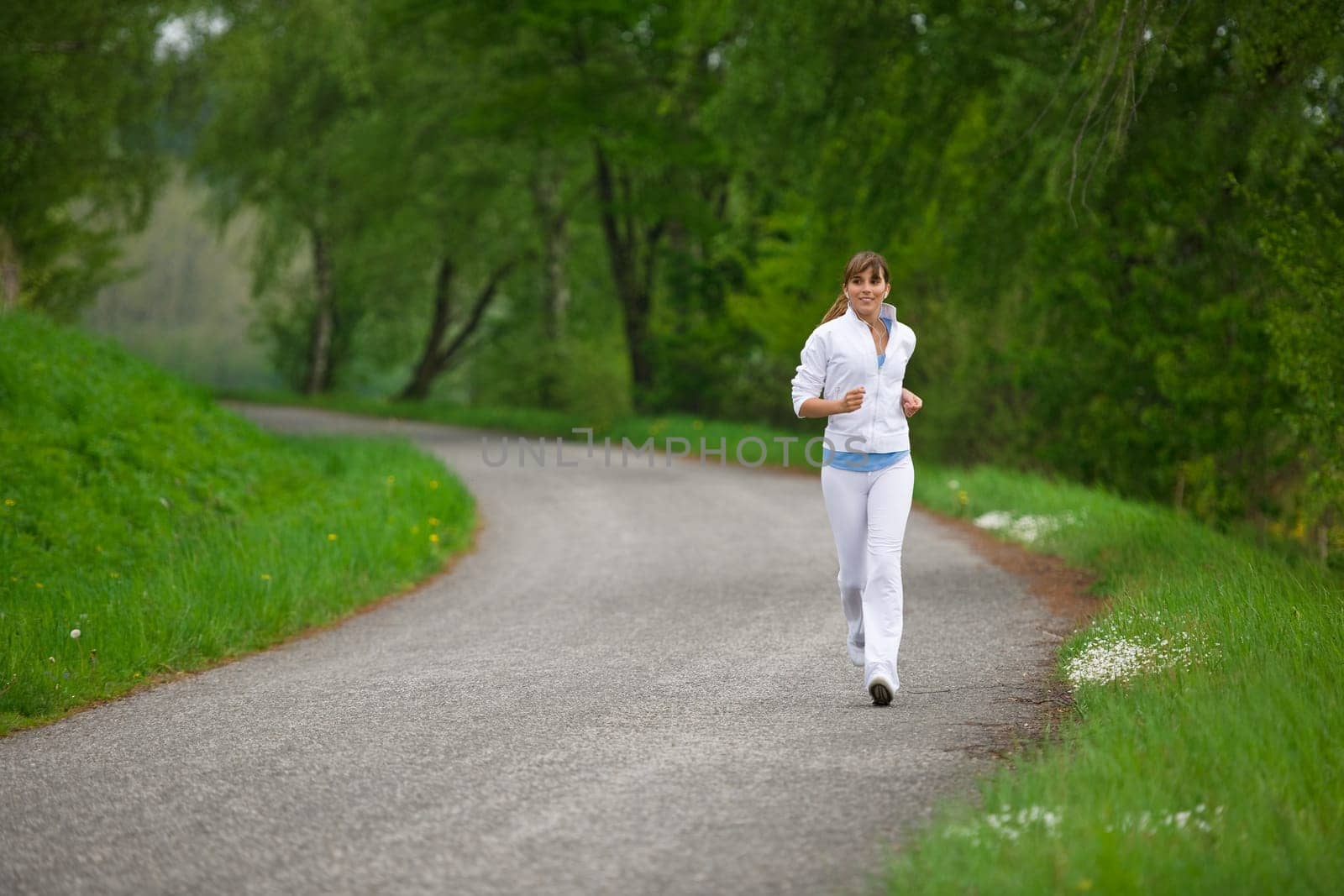 Jogging - sportive woman running on road in nature