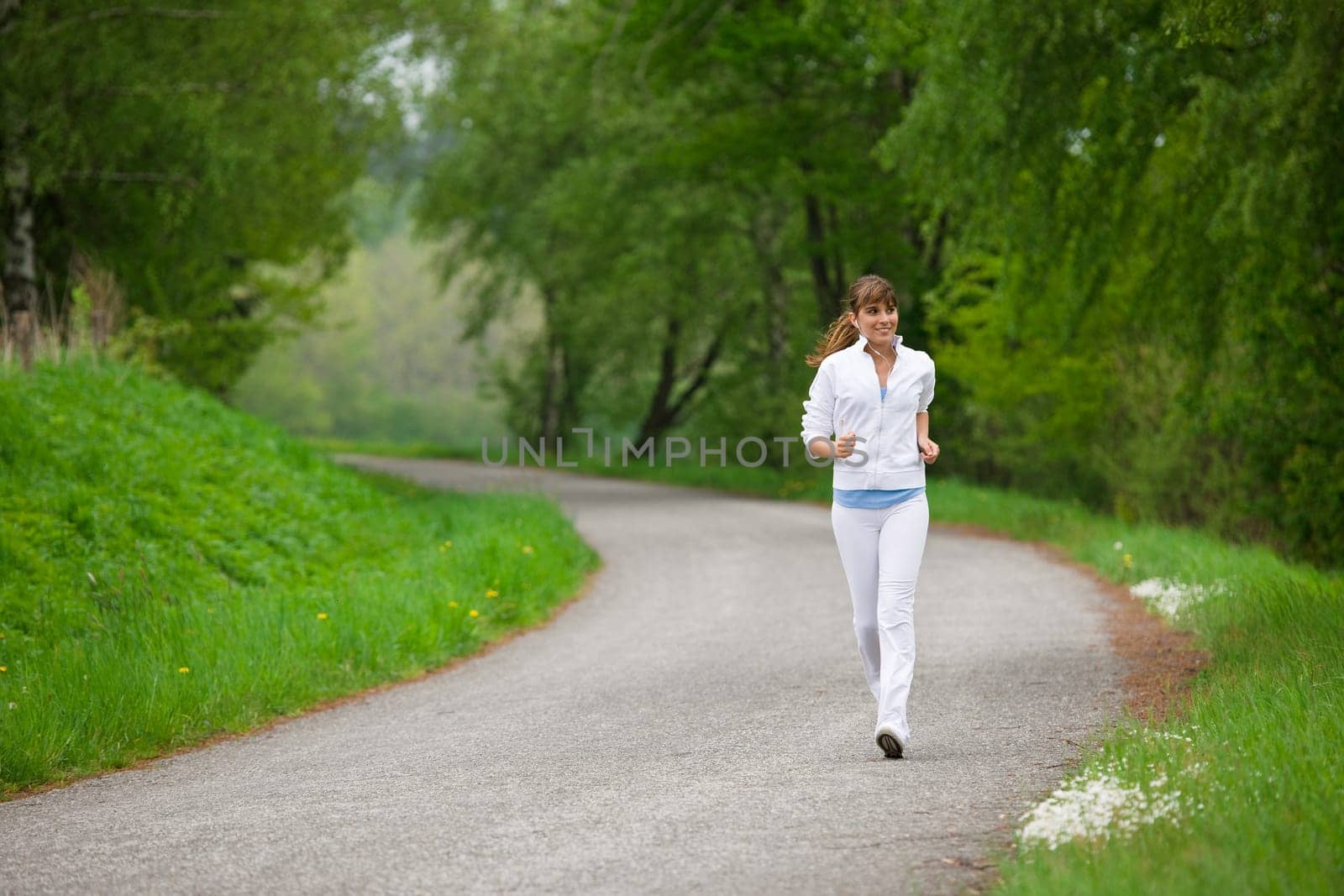 Jogging - sportive woman running on road in nature