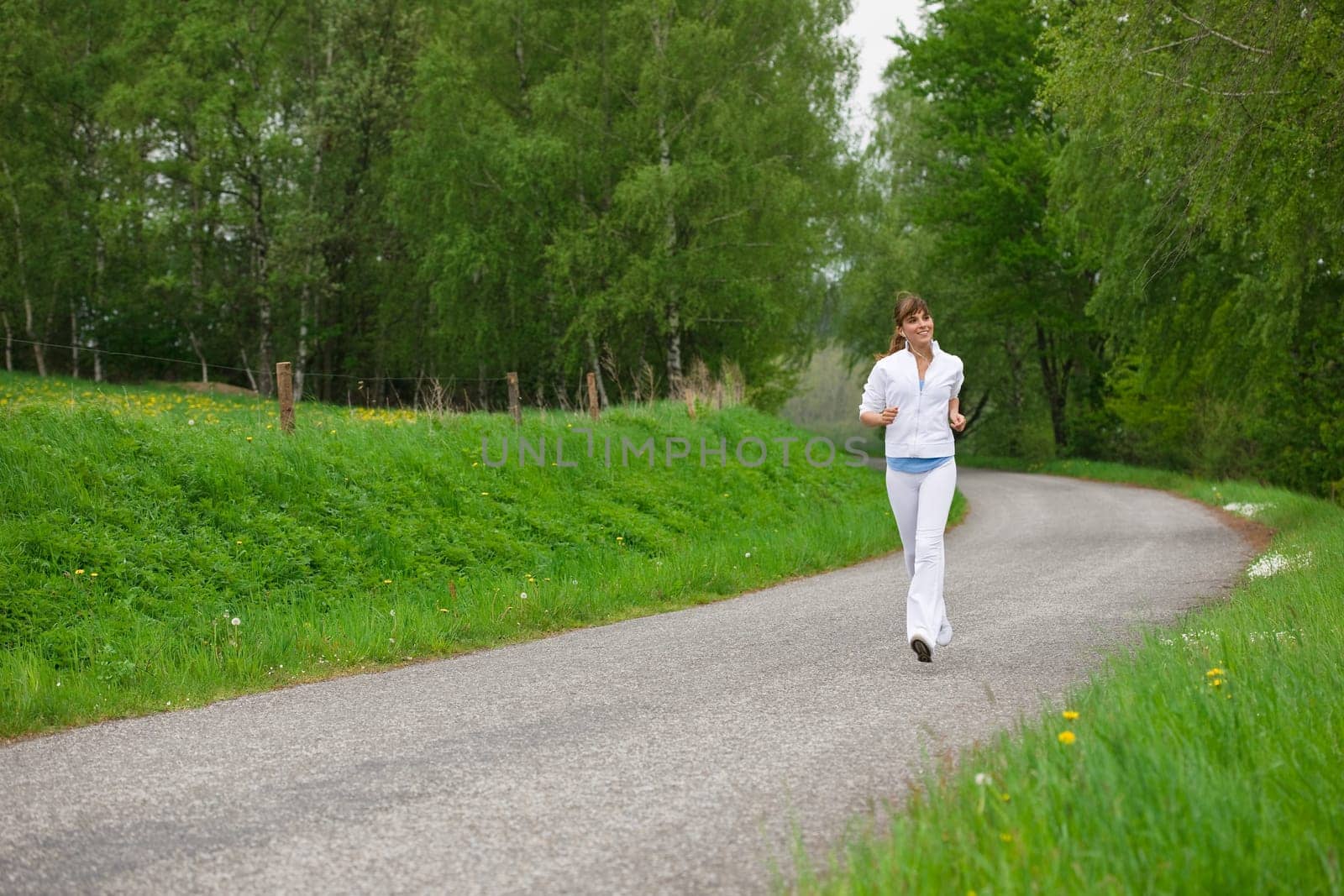 Jogging - sportive woman running on road in nature