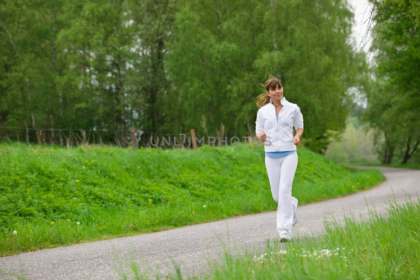Jogging - sportive woman running on road in nature