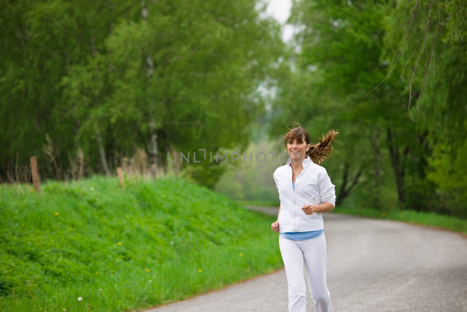 Jogging - sportive woman running on road in nature