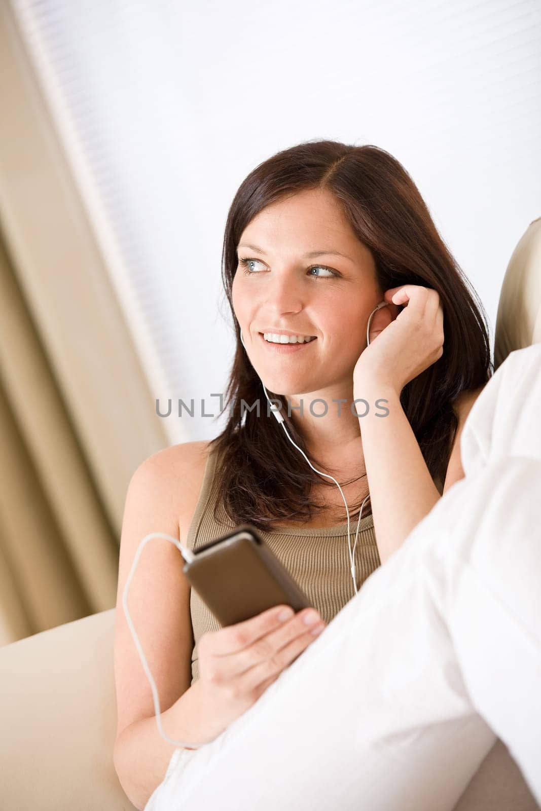Woman holding music player listening on sofa home
