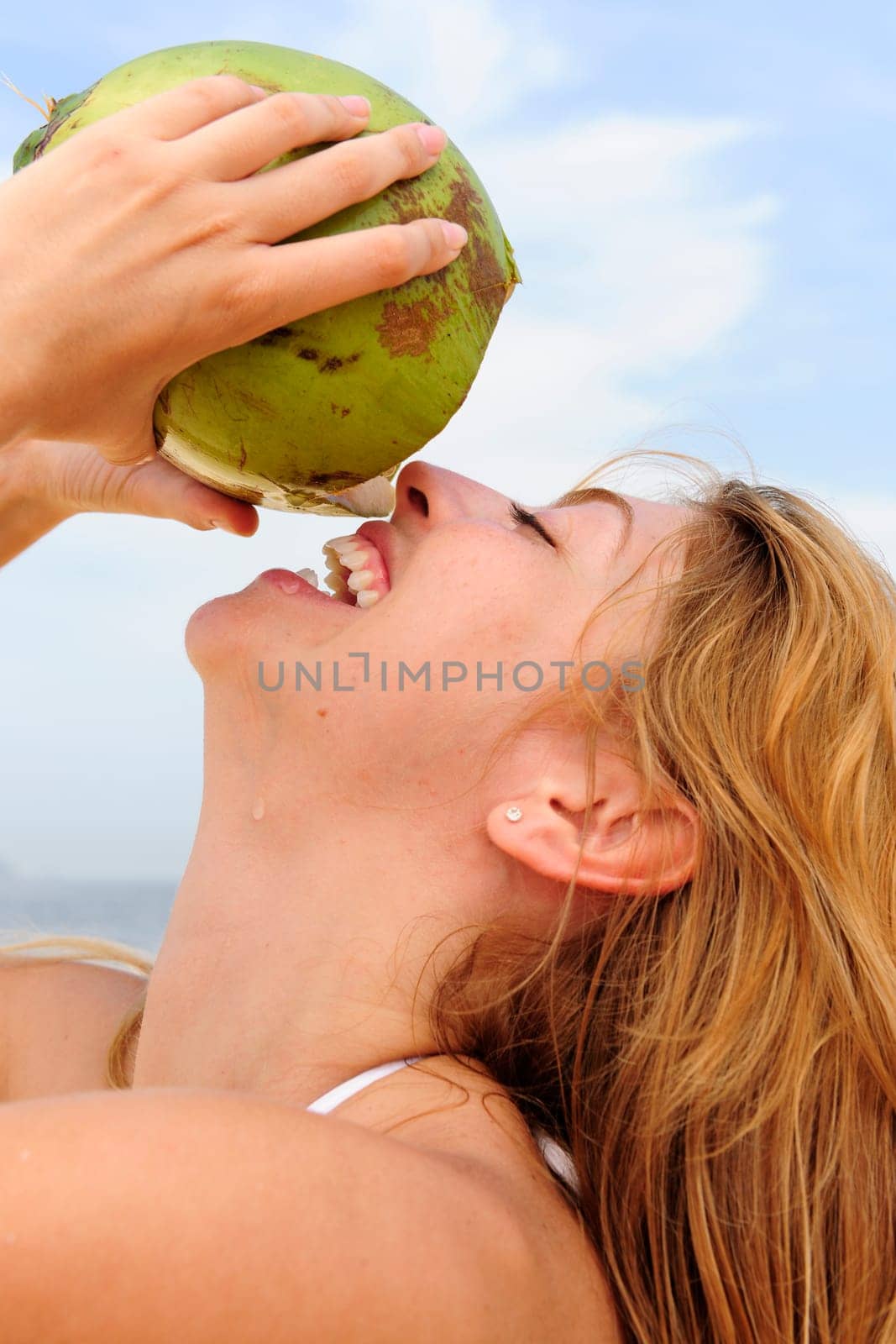 Woman drinking coconut water on the beach