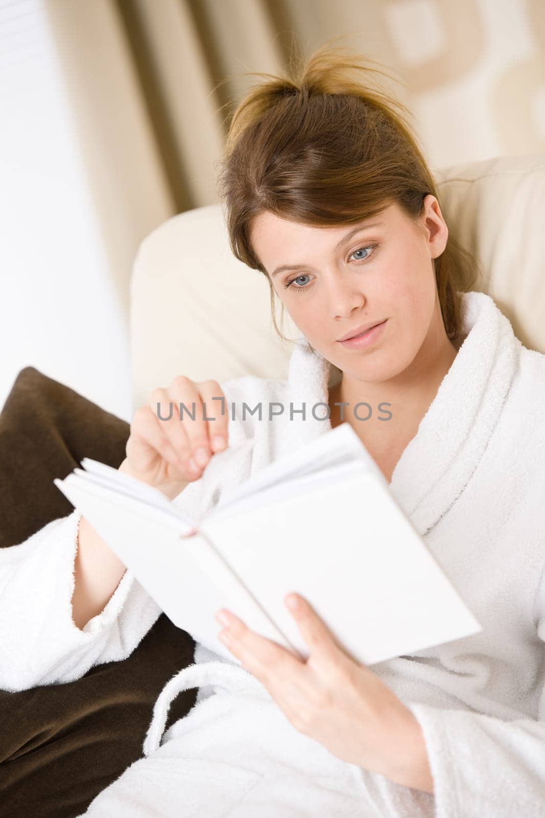 Young woman in bathrobe reading book