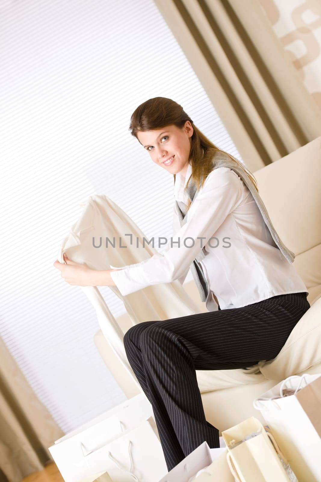 Young business woman sitting on sofa with shopping bag