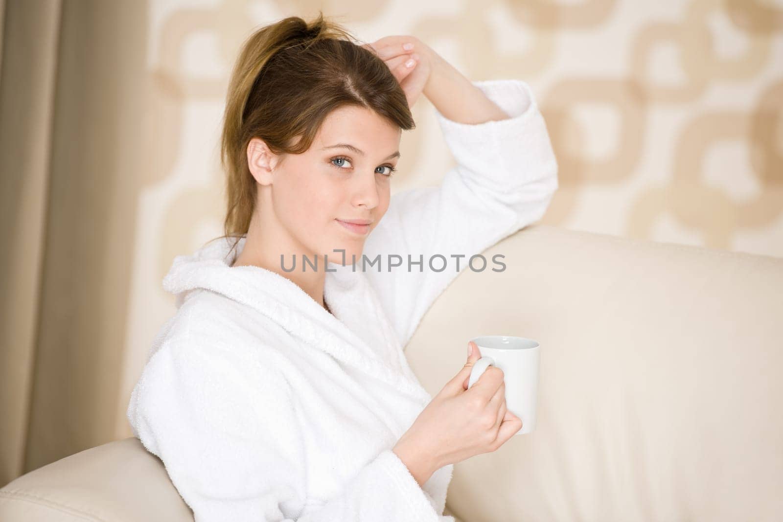 Young woman in white bathrobe with coffee