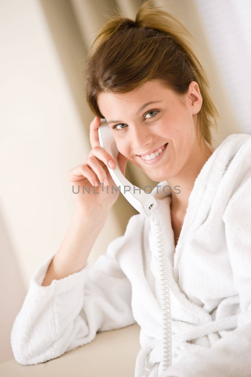 Happy woman in white bathrobe with phone