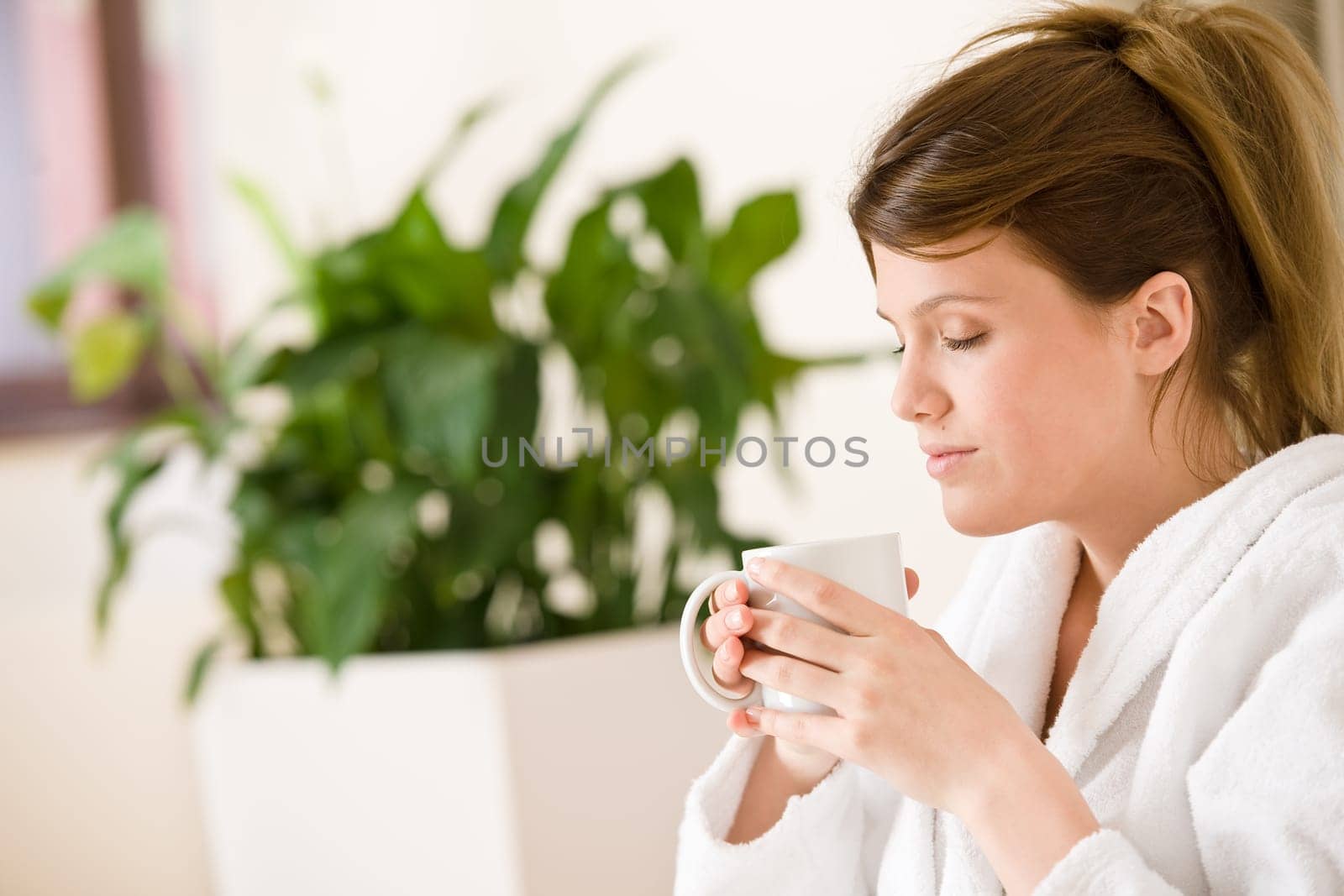 Young woman in white bathrobe with coffee