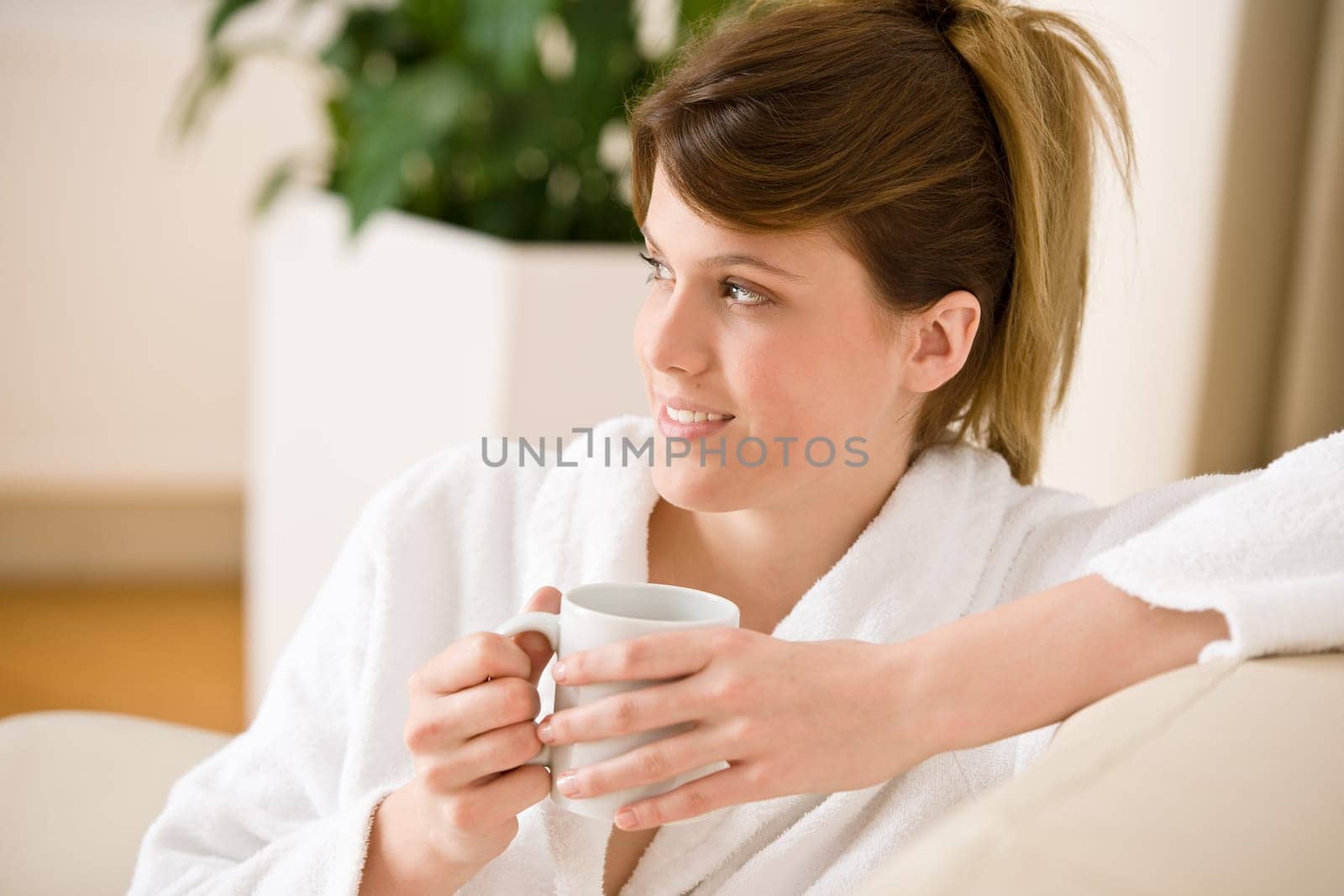 Young woman in white bathrobe with coffee