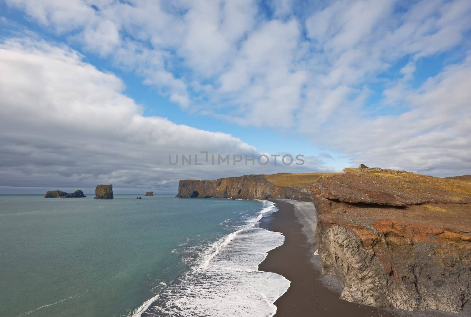 Black sand beach with Lundadrangur Rock Arch in Dyrholaey, South