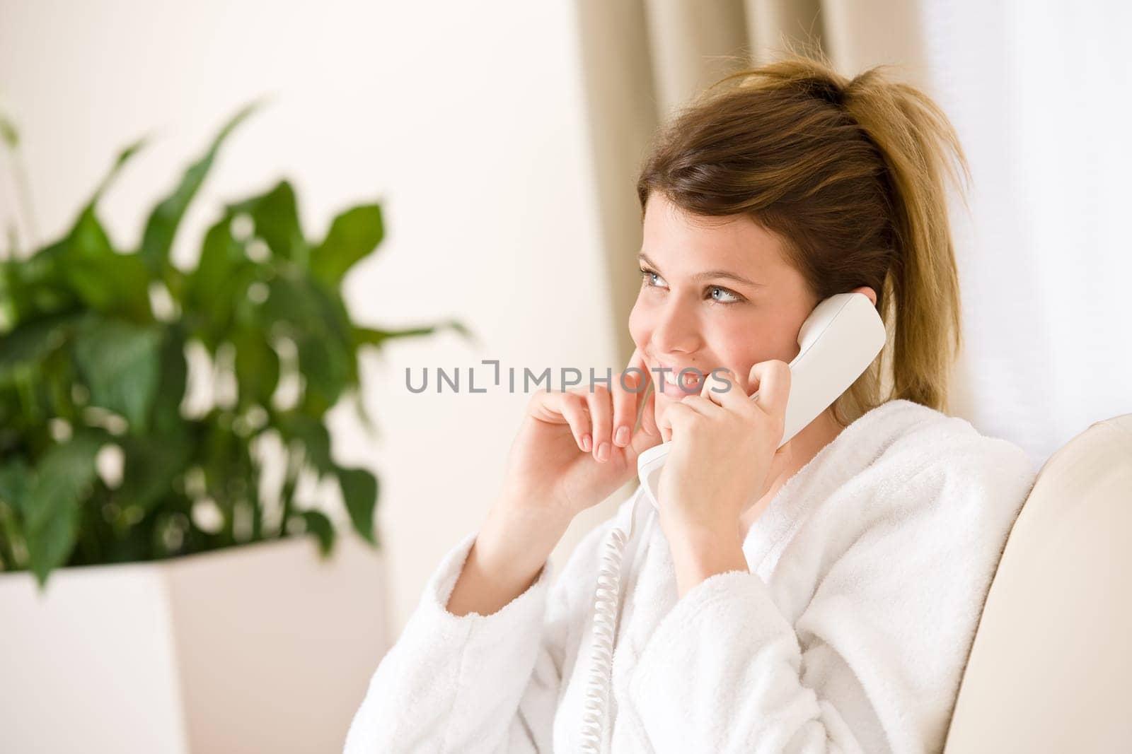 Happy woman in white bathrobe with phone home