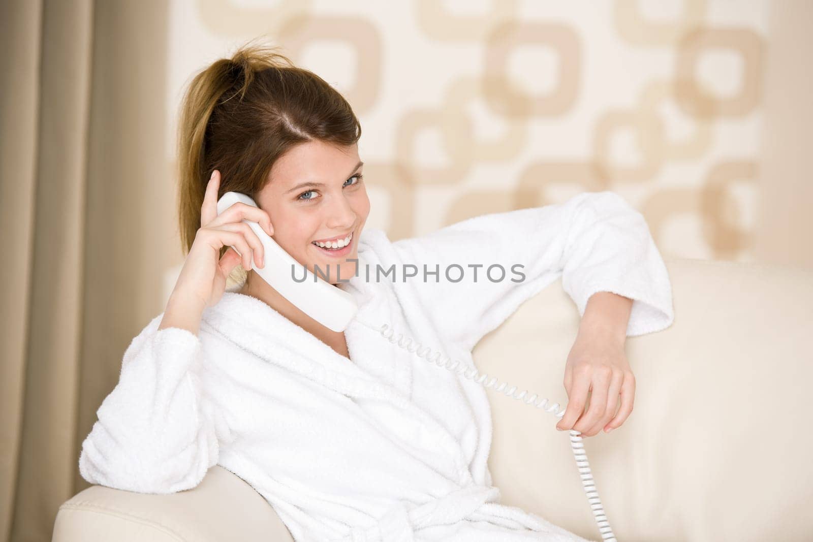Happy woman in white bathrobe with phone