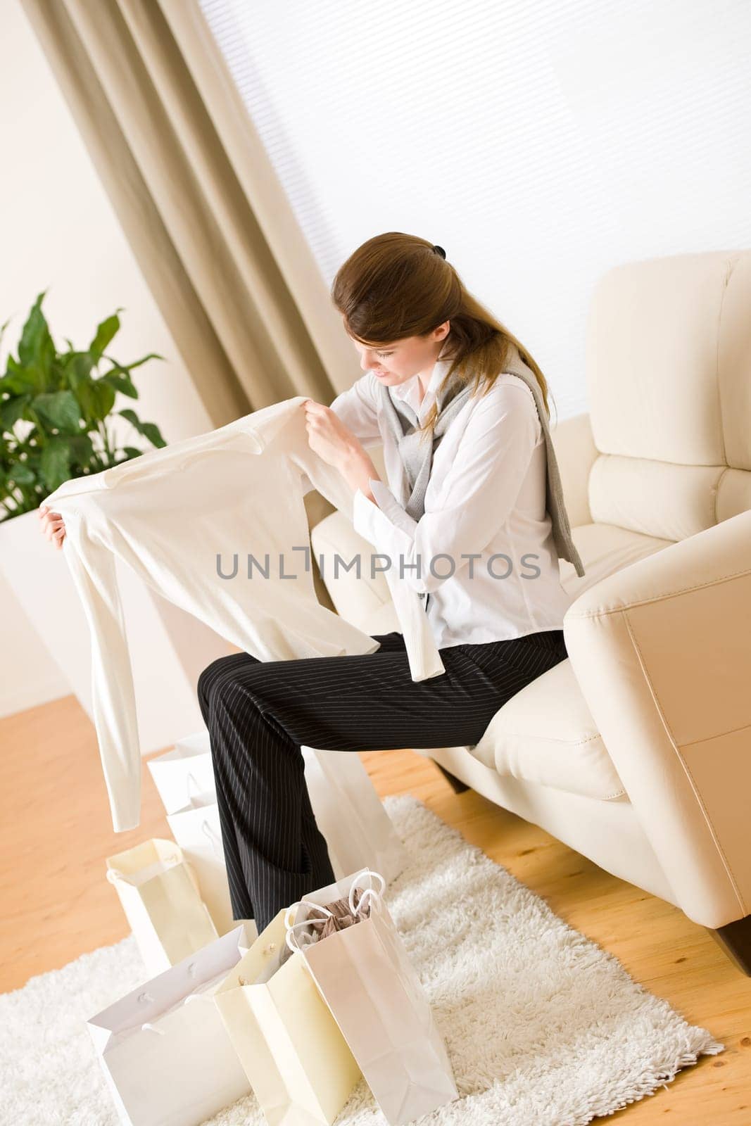 Young business woman sitting on sofa with shopping bag