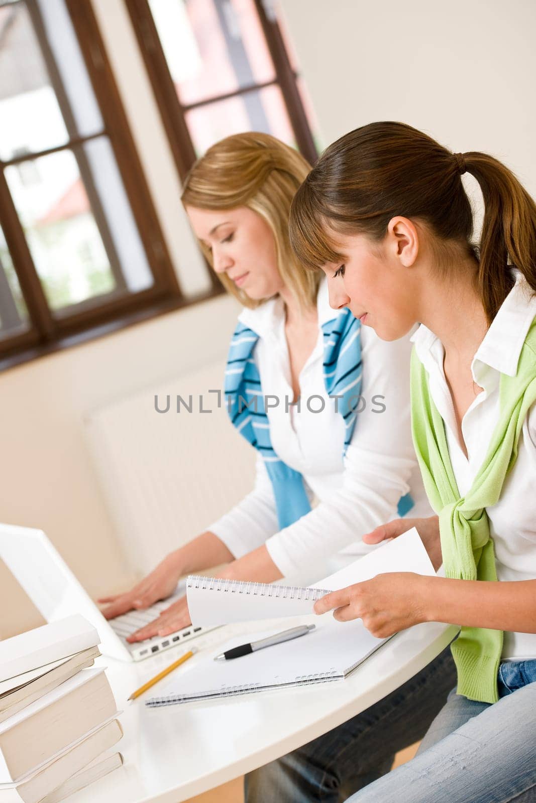 Student at home - two woman with book and laptop