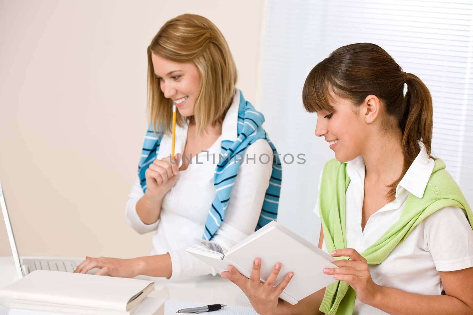 Student at home - two woman with book and laptop